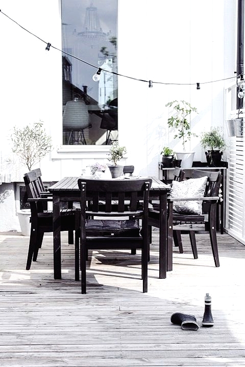 a Nordic black and white space with a simpel black wood dining set, a black table and lots of potted greenery to refresh the space