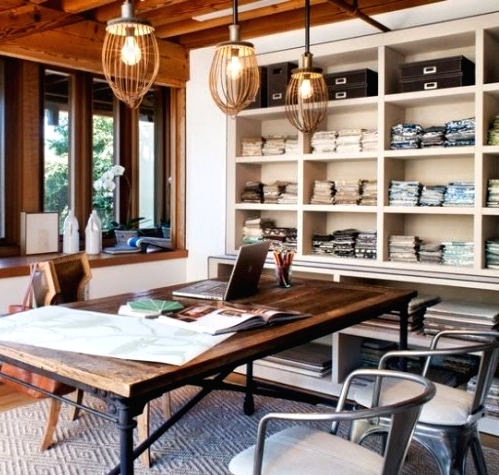 an eclectic home office with industrial touches, with wooden beams, built-in shelving units, an industrial metal and wood desk and metal chairs