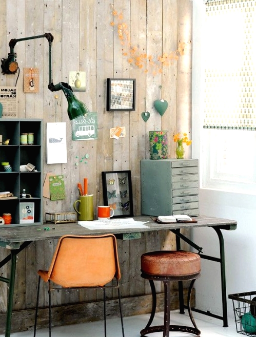 an industrial home office with reclaimed wood walls, a vintage wooden desk, leather chairs and stools, a metal sconce