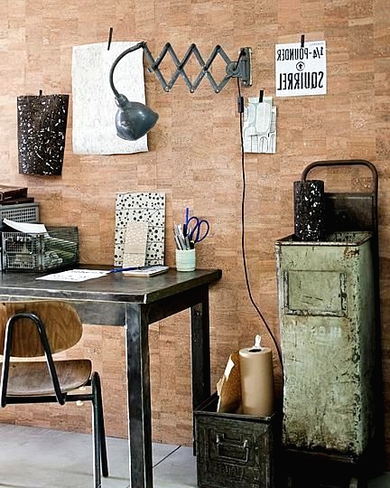 an industrial home office with a brick wall, a black wooden desk, a metal and plywood chair, a metal storage cabinet, a grey wall sconce
