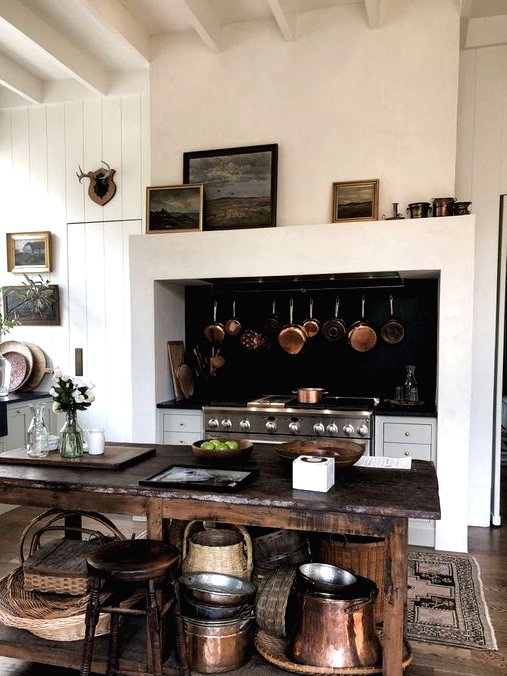 a modern farmhouse white kitchen with wooden beams on the ceiling, a vintage stained kitchen island and a matching stool