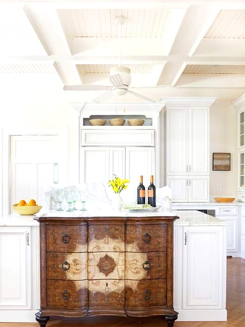 a white farmhouse kitchen with shaker style cabinets and a unique kitchen island - a large matching one with a refined vintage sideboard integrated is amazing