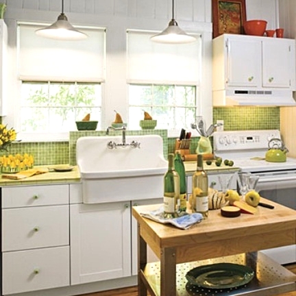 a white kitchen with shaker cabinets, a neon green tile backsplash and countertops plus a small stained table as a kitchen island