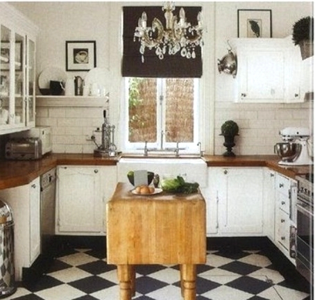 an elegant black and white kitchen with shaker style cabinets, butcherblock countertops, a checked floor, a stained folding table as a kitchen island