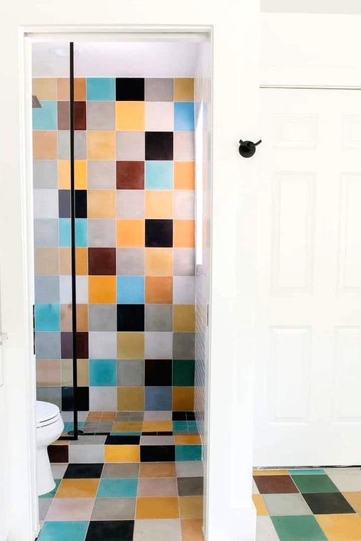 a modern bathroom clad with colorful tiles, with white appliances and a vanity that balance out the bold tiles