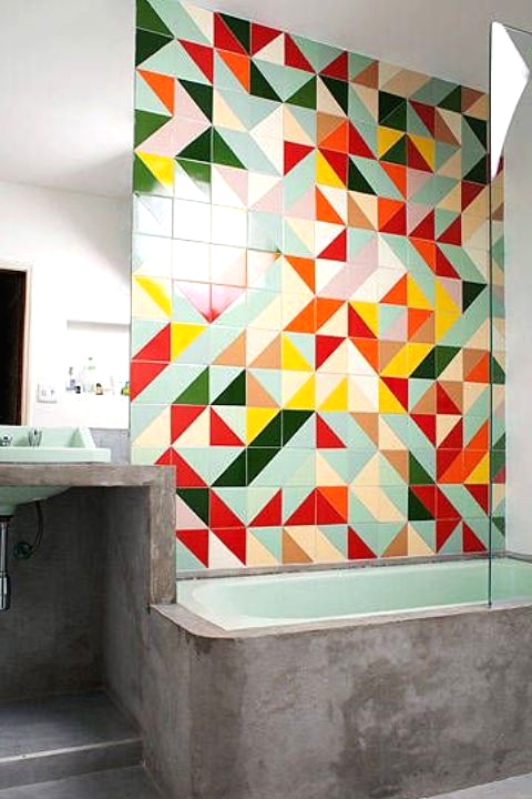 a modern bathroom with concrete and super bright geometric tiles accenting the green bathroom is amazing