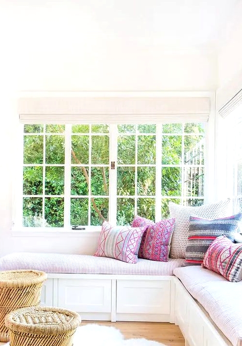 a cozy and inviting nook with a corner window, a corner daybed with colorful pillows and rattan stools is very chic and lovely