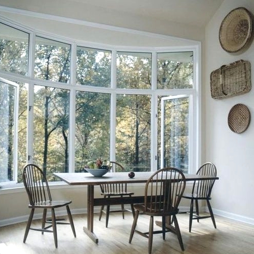 a farmhouse dining zone by a large bow window, with a vintage table and chairs plus decorative baskets on the wall