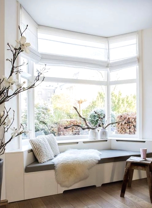 a lovely bow window with a windowsill daybed with pillows make up a lovely reading nook in the space