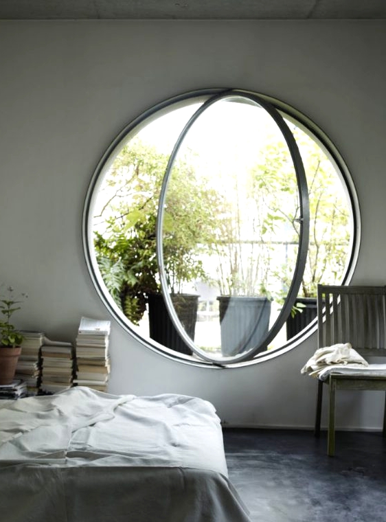 a neutral and airy bedroom done with a round pivot window, which allows fresh air in easily