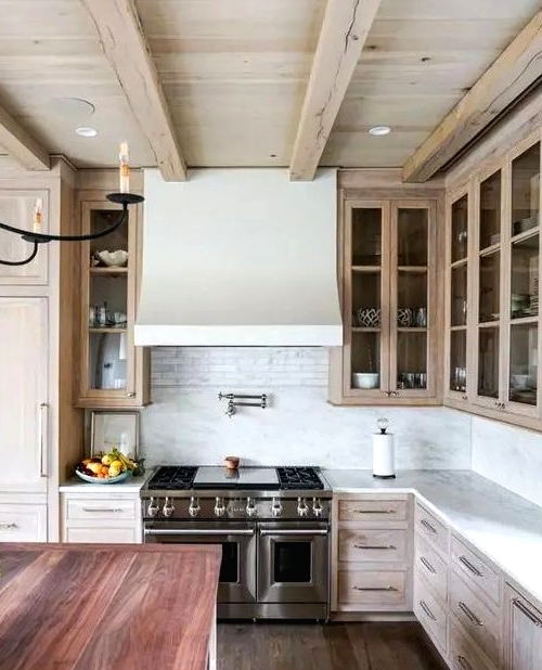 a catchy and welcoming kitchen with a whitewashed ceiling and cabinets, with a reclaimed wood floor and a kitchen island with a reddish countertop