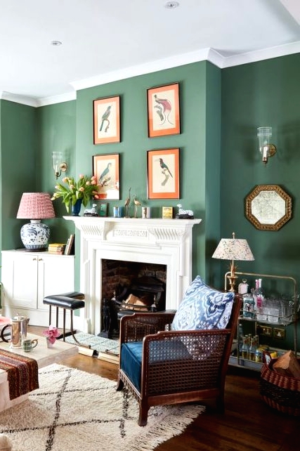 an elegant living room with calming green walls, a fireplace with a vintage mantel, a gallery wall and dark and light furniture