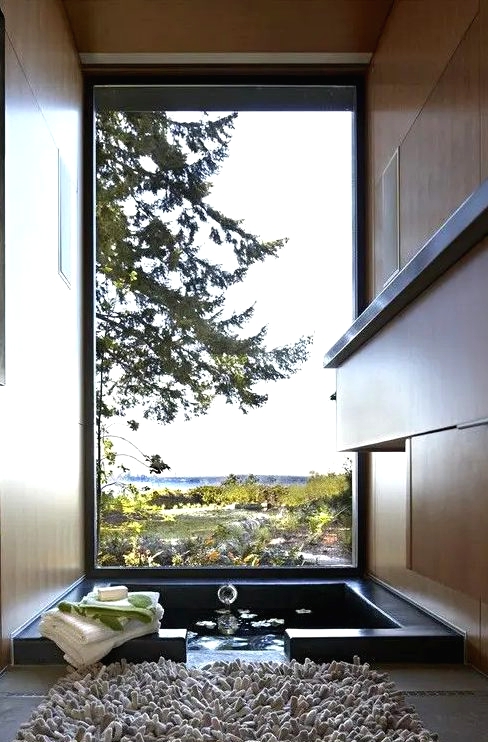 a gorgeous bathroom with a view, with an ofuro tub and a fluffy rug is a real relaxation oasis