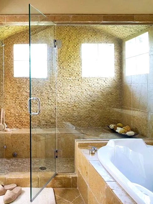 a beautiful warm-colored bathroom with a large shower space with glass doors and a bathtub clad with tiles