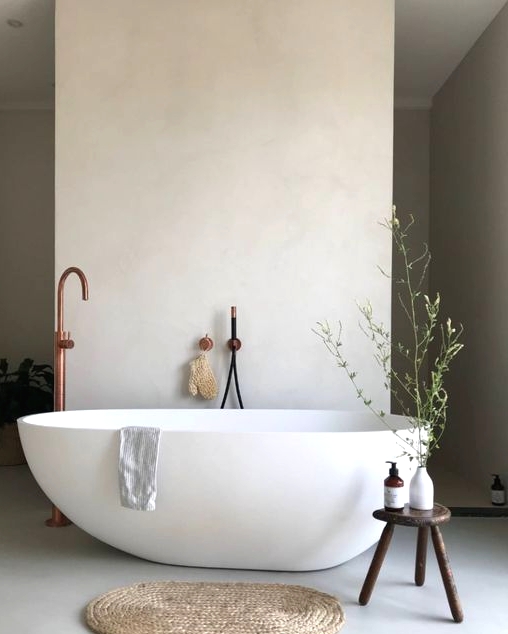 a beautiful contemporary spa bathroom with an oval tub, a dark-stained sotol, a jute rug and some greenery