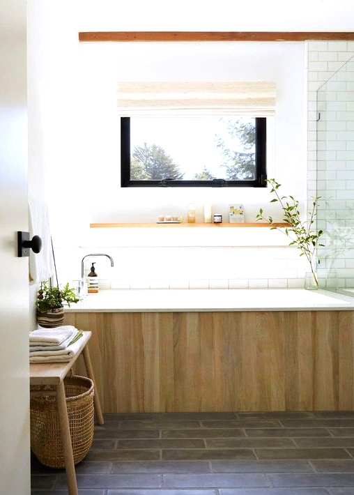 a spa-like bathroom in neutrals, with a glass-enclosed shower, a bathtub clad with wood and a wooden bench with a basket