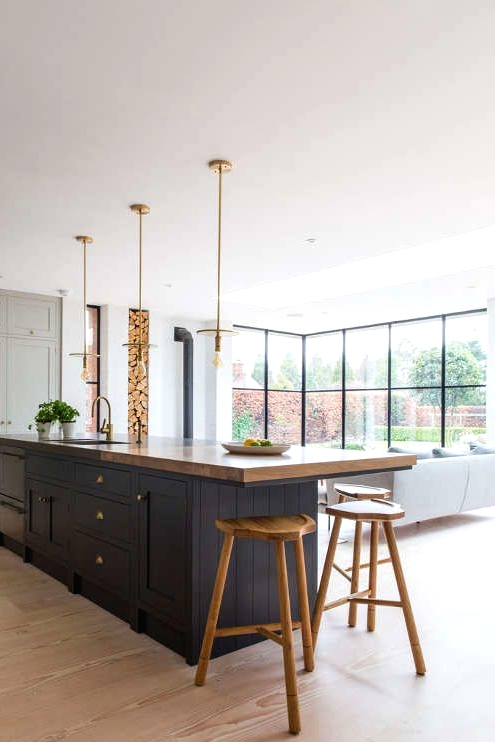a contemporary light grey kitchen with a contrasting navy kitchen island and a small eating space with some stained wood stools