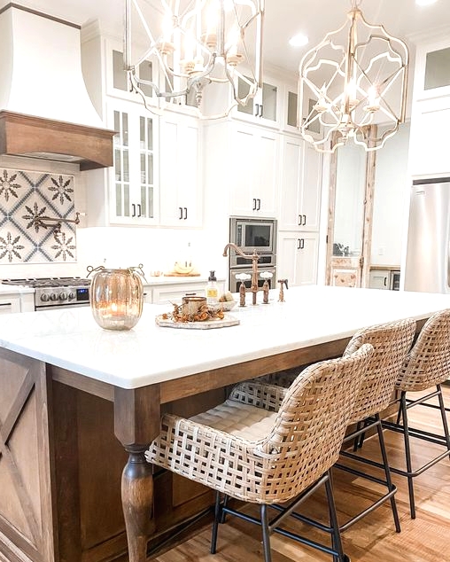 a fabulous vintage kitchen with white cabinets, a stained kitchen island with vintage legs, chic pendant lamps and woven stools