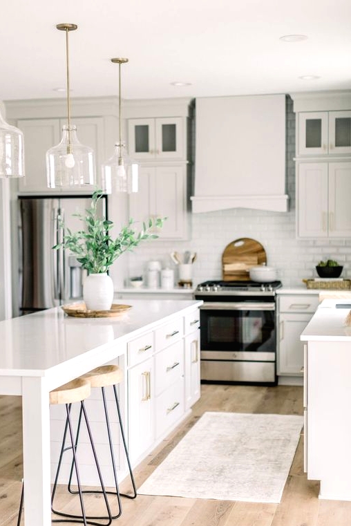 a fresh white kitchen with a farmhouse feel, with a large kitchen island with storage and a seating zone and glass pendant lamps