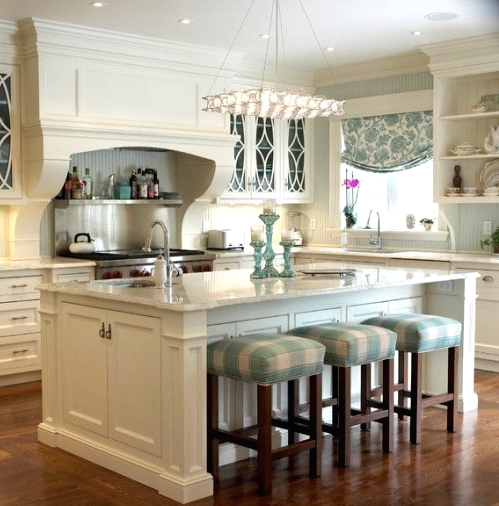 a white farmhouse kitchen with shaker style cabinets, white stone countertops, a large kitchen island with a seating space and striped stools