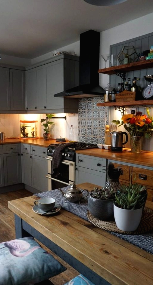 a cozy slate grey kitchen with shaker style cabinets, butcherblock countertops, a printed tile backsplash and an eatign zone here