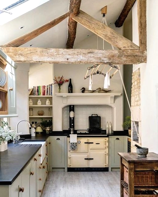 a small and cozy barn kitchen in neutrals, with a skylight, a reclaimed wooden beam, dove grey kitchen cabinets with black countertops and a wooden kitchen island