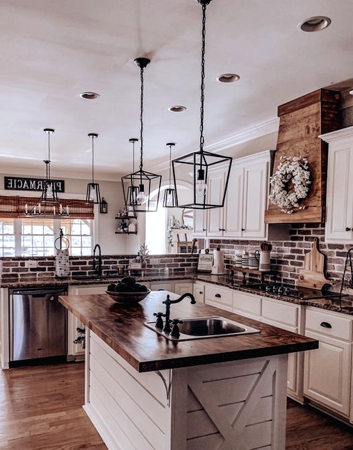 a welcoming barn kitchen with white cabinets and a planked kitchen island, stone and butcherblock countertops, black pendant lamps