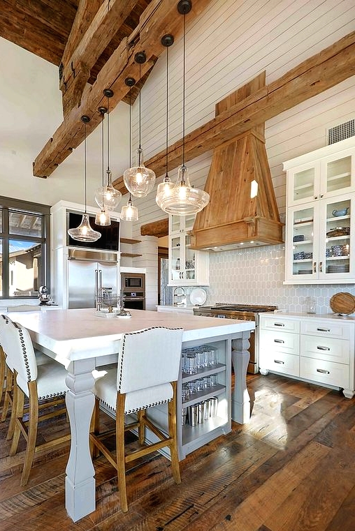 a white barn kitchen with a planked ceiling, wooden beams, white cabinetry, a large kitchen island that doubles as a table