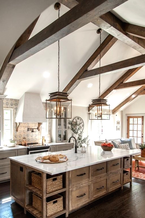 a welcoming neutral kitchen with white shaker style cabinets, a stained kitchen island, wooden beams and vintage pendant lamps