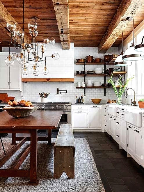 a white country kitchen with shaker style cabinets and a tiled hood, a reclaimed wood ceiling with beams and a shabby chic dining set