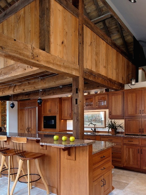 a light-stained wood kitchen with wooden beamds and tall stools is very warm and welcoming as it's fully made of wood