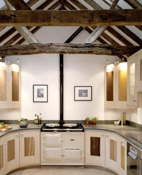 a white kitchen with sleek cabinets, a vintage cooker and black countertops, reclaimed wooden beams on the ceiling