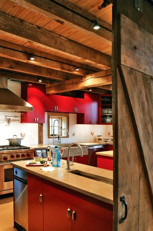 a barn kitchen with weathered wooden beams on the ceiling, a bright red kitchen with sleek and plain cabinets, stainless steel appliances
