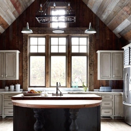 a vintage barn kitchen with reclaimed wood walls and ceiling, white vintage cabinets, a graphite grey kitchen island with butcherblock countertops
