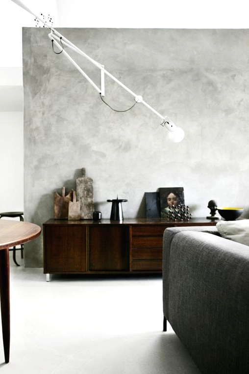 a modern living room with grey limewashed walls, a grey sofa, dark-stained furniture and a sconce