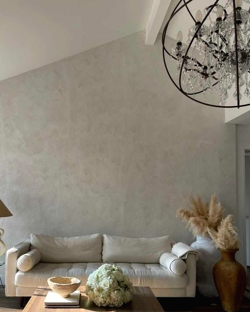 a pretty and airy living room with light grey limewashed walls, a creamy sofa, a low coffee table, pampas grass in vases