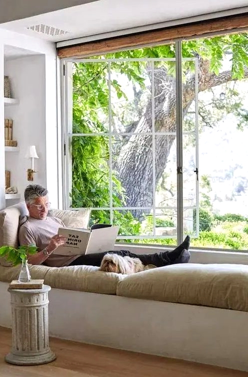 a large French window with a built-in daybed and shelves, with sconces and a refined side table make up a gorgeous nook