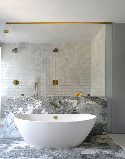 a neutral bathroom with a shower space clad with grey zellige tiles, with a bathtub space done with grey marble is wow