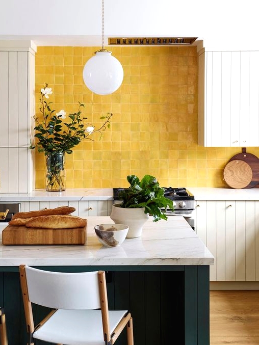 a neutral farmhouse kitchen with planked cabinets, a dark green planked kitchen island and a yellow zellige tile backsplash