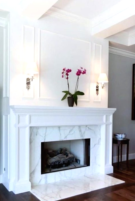 a chic and stylish marble fireplace with some marble on the floor and a vintage white mantel over it is refined