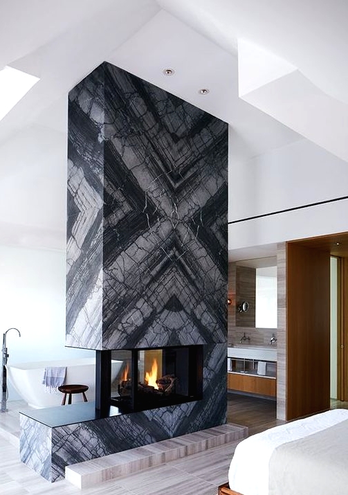 a grey marble slab fireplace separates the sleeping and bathing zone and makes them cozy and warm