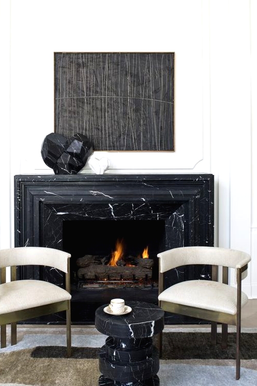 a refined nook with a black marble fireplace and a matching side table, gorgeous brass and velvet chairs