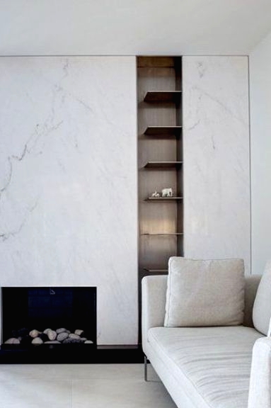 a sophisticated neutral living room in contemporary style, with a white marble fireplace, built-in shelves and a white sofa