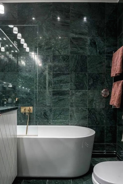 green marble tiles covering the whole bathroom make it a refined and a bit moody space