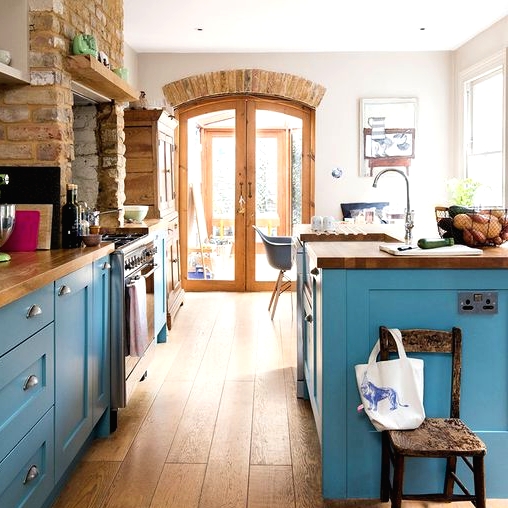 a chic and stylish kitchen with stone blue cabinetry, butcherblock countertops, a brick backsplash is amazing