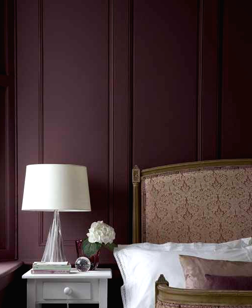 a refined and chic bedroom with aubergine walls, a neutral upholstered bed, a vintage nightstand and a lamp is amazing