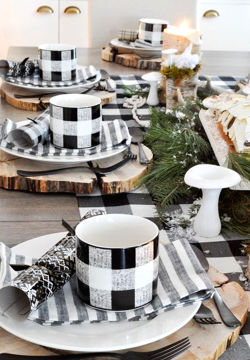 a cozy and simple buffalo check Christmas tablescape with wood slice placemats, striped napkins, buffalo check mugs and a table runner, evergreens and mushrooms