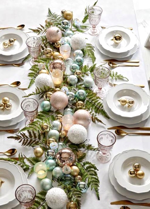 a pretty pastel Christmas tablescape with fern leaves, pastel and metallic ornaments, chic plates and gold cutlery