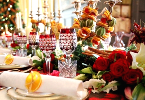 a bold Christmas table setting with a red printed tablecloth, bold lush florals, tablle elegant candelabras and red glasses with detailing