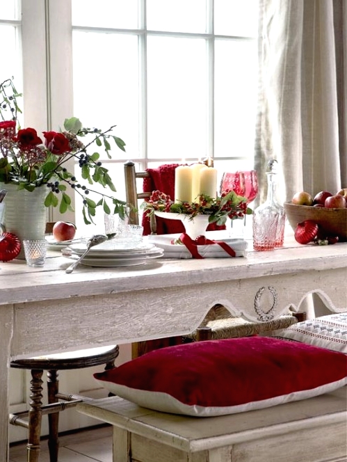 a relaxed Christmas tablescape with a bold red floral centerpiece with greenery, a candle arrangement with berries, neutral porcelain and vintage ornaments